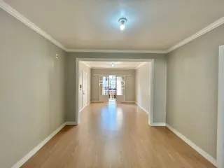 Hall de entrada com piso de madeira clara e paredes cinzas.
