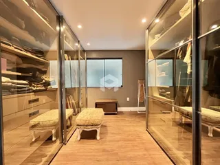 Interior de um corredor com paredes de vidro e piso de madeira.