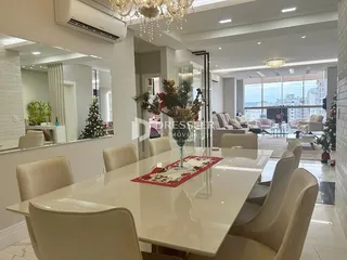 Uma mesa de jantar branca com cadeiras brancas é vista em um ambiente interno.