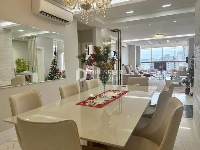 Uma mesa de jantar branca com cadeiras brancas é vista em um ambiente interno.