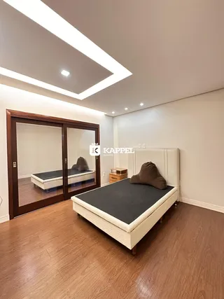 Quarto com cama e piso de madeira clara.
