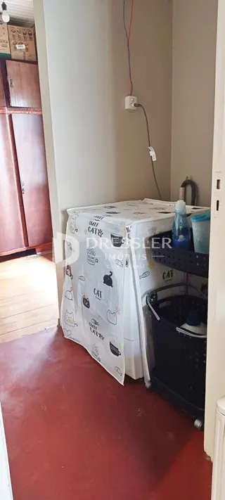 Hall de entrada com piso vermelho e parede branca.