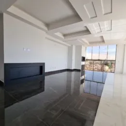 Foto de um ambiente interno amplo com piso escuro e paredes brancas.