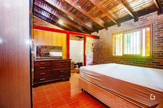 Um quarto com teto de madeira e paredes de tijolo aparente.