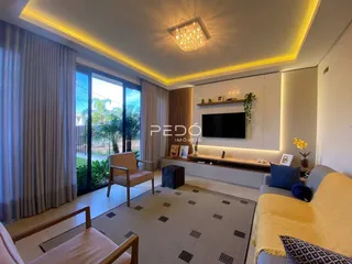 Sala de estar moderna com grandes janelas e decoração clara.