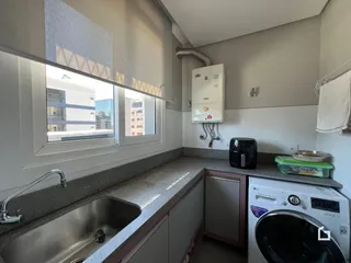 Vista da cozinha com janela e máquina de lavar roupa.