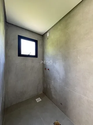 Corredor interno com paredes cinzas e uma janela retangular.