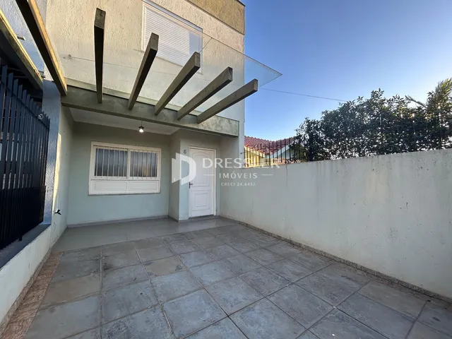 Vista da fachada de uma residência com área externa pavimentada.