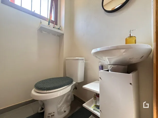 Foto de um banheiro interno com vaso sanitário e pia brancos.