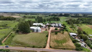 Vista aérea de uma propriedade rural com campos verdes e estruturas de armazenamento.