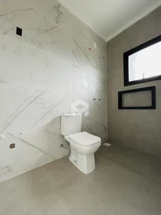 Foto interna de um banheiro com revestimento de mármore e piso claro.