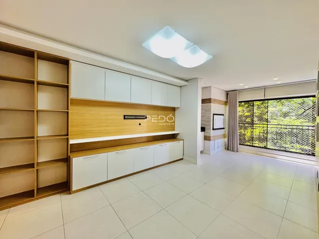 Foto de uma sala de estar com armários de madeira e piso claro.