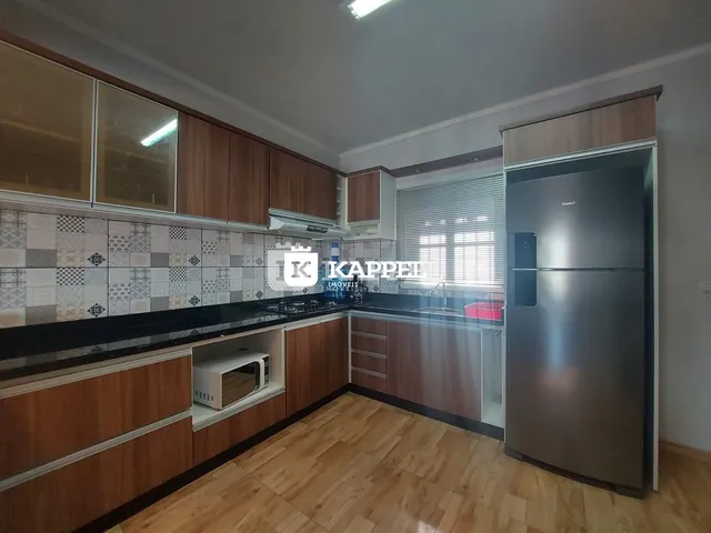 Cozinha com armários de madeira e bancadas escuras.