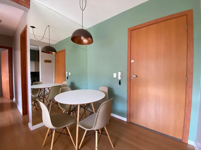 Uma sala de jantar com mesa redonda e cadeiras claras.