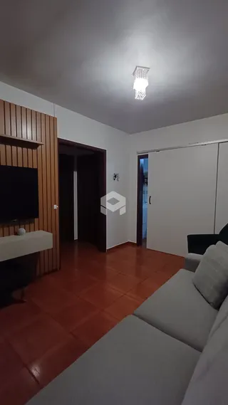 Sala de estar com piso de cerâmica avermelhada e painel de madeira.