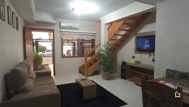 Sala de estar com escadaria de madeira e sofá.