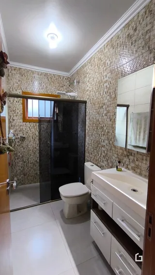 Foto de um banheiro com revestimento de cerâmica e louças brancas.