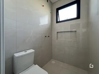 Banheiro com revestimento de cerâmica branca e janela.