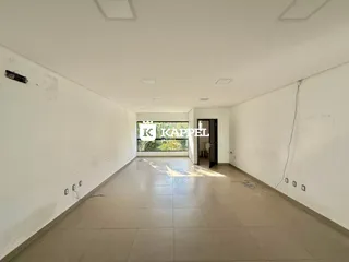 Corredor longo com piso de cerâmica e paredes brancas em um imóvel.