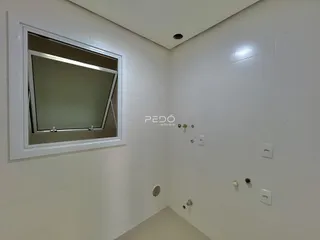 Vista de um canto de ambiente interno com paredes brancas e revestimento.