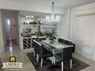 Sala de jantar com mesa de vidro e cadeiras escuras em um imóvel no Brasil.