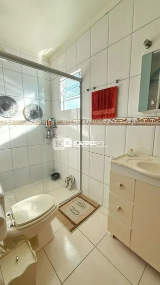 Banheiro com piso de cerâmica e box de vidro.