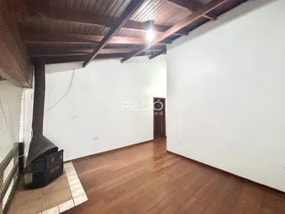 Imagem de uma sala com piso de madeira e vigas expostas.