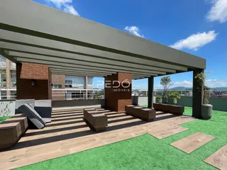 Área externa com deck de madeira e gramado artificial.