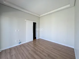 Vista interna de um ambiente com piso de madeira clara e paredes brancas.