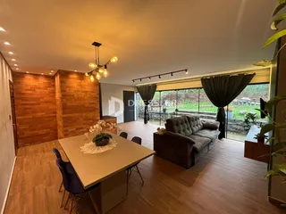 Sala de estar com piso de madeira e portas de vidro que dão para o exterior.
