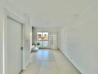 Hall de entrada com piso claro e paredes brancas.