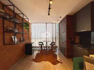 Ambiente interno com parede de tijolos aparentes e piso de madeira clara.