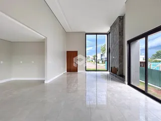 Interior de uma sala ampla com piso de porcelanato claro e grandes portas de vidro.
