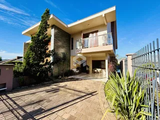 Fachada de uma casa moderna com jardim e portão de ferro.