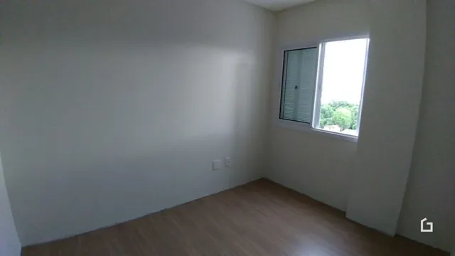 Interior de um cômodo com piso de madeira e paredes brancas.