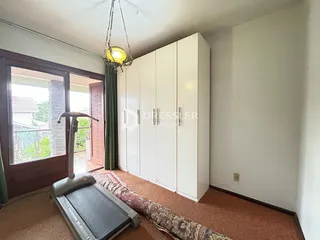 Quarto com armário branco e porta de vidro abrindo para o exterior.