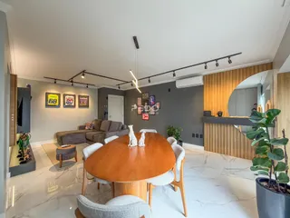 Sala de jantar com mesa de madeira e sofá em ambiente moderno.