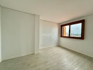 Ambiente interno de uma sala com piso claro e janela de madeira.