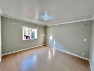 Uma sala de estar com piso de madeira clara e paredes cinzas.