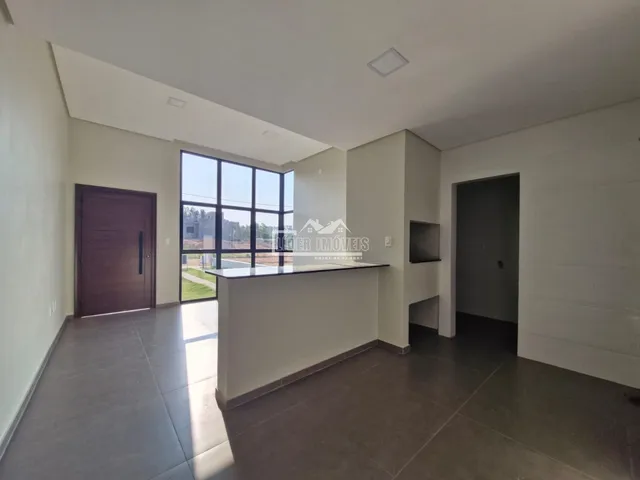 Ambiente interno de uma sala com grandes janelas e piso de cerâmica.
