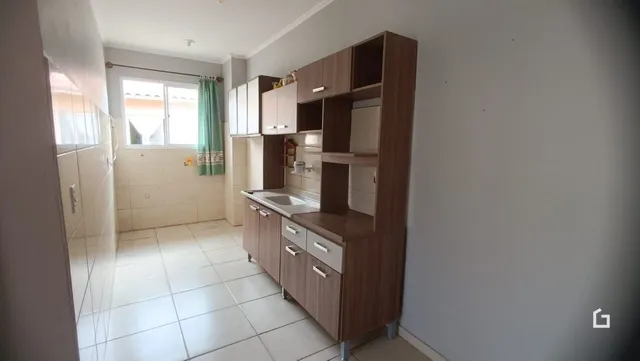 Interior da cozinha com armários de madeira e piso de cerâmica clara.