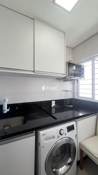 Cozinha moderna com armários brancos e bancadas escuras.