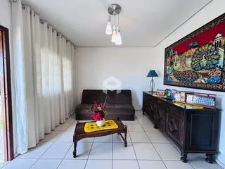 Sala de estar com cortinas brancas e móveis de madeira escura.