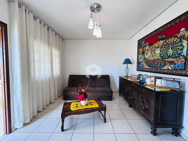 Sala de estar com cortinas brancas e móveis de madeira escura.