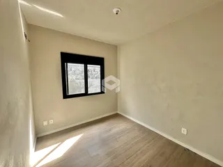 Ambiente interno de uma sala com piso de madeira clara e janela.