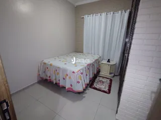 Quarto com cama e cortinas brancas em um imóvel.