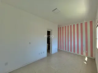 Interior de uma sala com paredes brancas e detalhes em listras rosa.