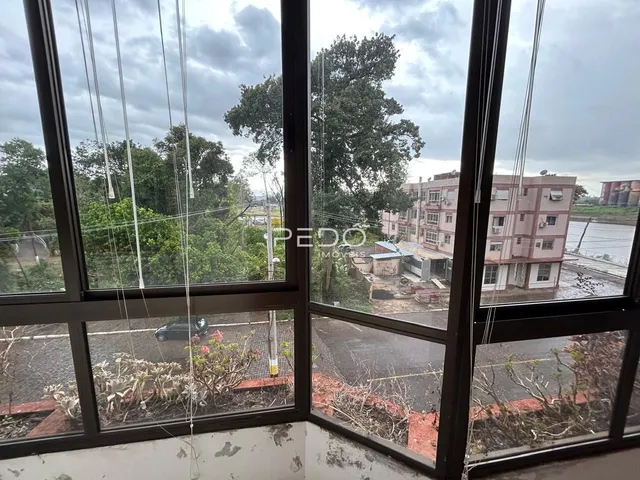 Vista externa de uma área arborizada e edifícios ao fundo da propriedade.