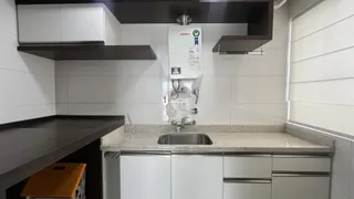 Foto de uma cozinha com armários brancos e bancada de granito.