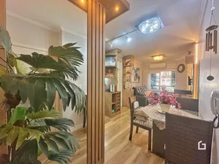 Ambiente interno de sala de estar e jantar com piso de madeira e plantas.